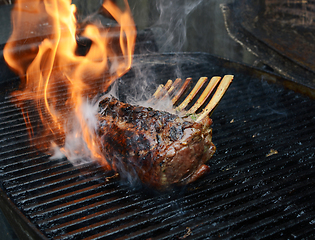 Image showing Rack of lamb on barbecue with flame and smoke