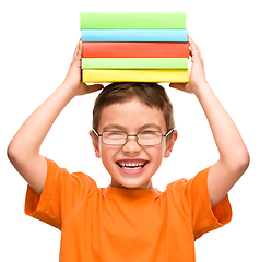 Image showing Little boy is holding a pile of books