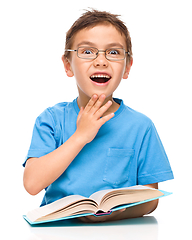 Image showing Astonished little boy is reading a book