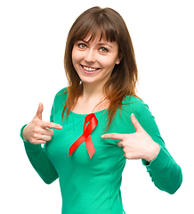 Image showing Woman is pointing to the red awareness ribbon