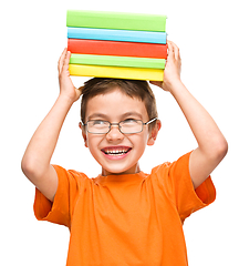 Image showing Little boy is holding a pile of books