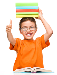 Image showing Little boy is holding a pile of books