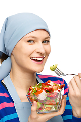 Image showing Young attractive woman is eating salad using fork