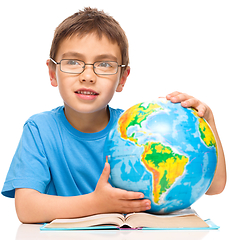 Image showing Little boy is examining globe