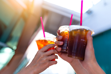 Image showing Friends holding iced coffee with sun flare