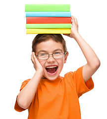 Image showing Little boy is holding a pile of books