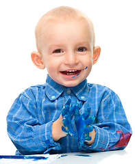 Image showing Little boy is playing with paints