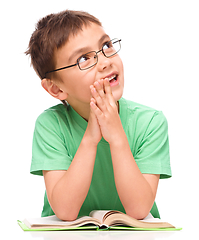 Image showing Young boy is daydreaming while reading book