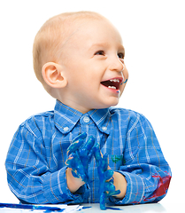 Image showing Little boy is playing with paints