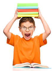 Image showing Little boy is holding a pile of books