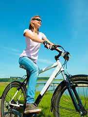 Image showing Young woman is sitting on her bicycle