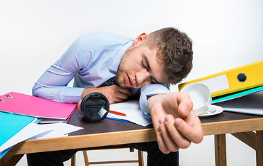 Image showing The young man is brazenly sleeping on the desktop during his working hours