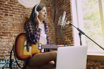 Image showing Woman recording music, playing guitar and singing at home