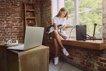 Image showing Woman recording music, playing guitar and singing at home