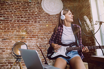 Image showing Woman recording music, playing guitar and singing at home