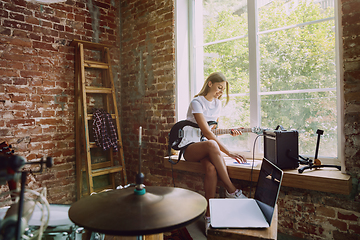 Image showing Woman recording music, playing guitar and singing at home