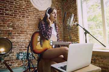 Image showing Woman recording music, playing guitar and singing at home