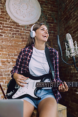 Image showing Woman recording music, playing guitar and singing at home