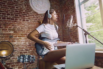 Image showing Woman recording music, playing guitar and singing at home