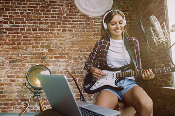 Image showing Woman recording music, playing guitar and singing at home