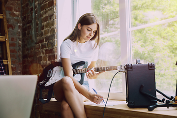 Image showing Woman recording music, playing guitar and singing at home