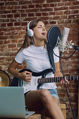 Image showing Woman recording music, playing guitar and singing at home