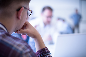 Image showing Business man writing notes while working on laptop