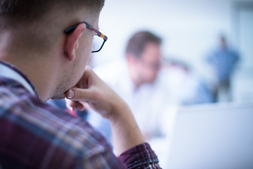 Image showing Business man writing notes while working on laptop