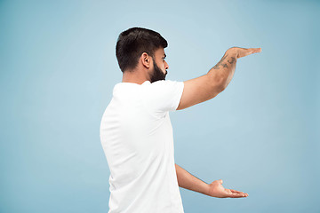 Image showing Half-length close up portrait of young man on blue background.