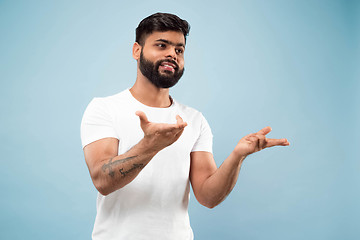 Image showing Half-length close up portrait of young man on blue background.