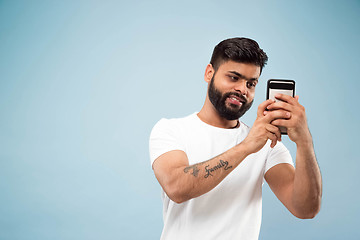 Image showing Half-length close up portrait of young man on blue background.