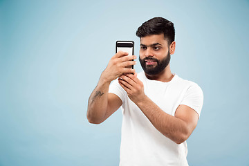 Image showing Half-length close up portrait of young man on blue background.