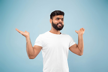 Image showing Half-length close up portrait of young man on blue background.