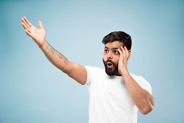 Image showing Half-length close up portrait of young man on blue background.