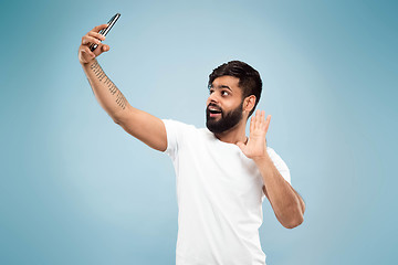 Image showing Half-length close up portrait of young man on blue background.