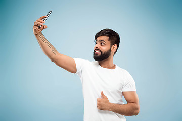 Image showing Half-length close up portrait of young man on blue background.