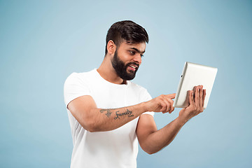 Image showing Half-length close up portrait of young man on blue background.