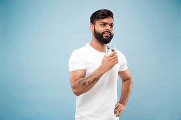 Image showing Half-length close up portrait of young man on blue background.