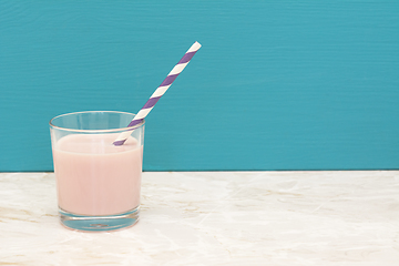 Image showing Delicious strawberry milkshake with a straw in a glass