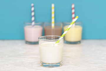 Image showing Fresh milk in front of a row of flavoured milkshakes