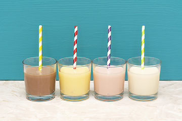 Image showing Milkshakes and fresh milk with retro paper straws in glass tumbl