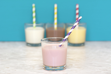 Image showing Strawberry milkshake in front of a row of flavoured milkshakes