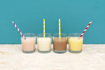 Image showing Flavoured milkshakes and milk with straws in glass tumblers