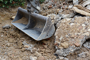 Image showing Heavy duty metal digger bucket among piles of rough rubble