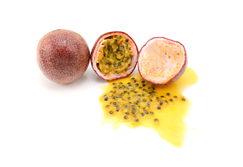 Image showing Whole and halved passion fruits with spilled juice and seeds