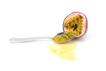 Image showing Spoon scooping out seeds from half a purple passion fruit