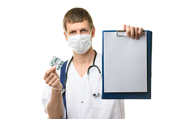 Image showing The doctor shows a tablet with a white sheet of paper in the frame, holds medicines in the other hand