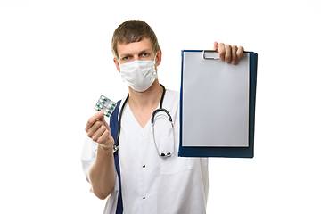 Image showing The doctor shows a tablet with a white sheet of paper in the frame, holds medicines in the other hand, focusing on the tablet