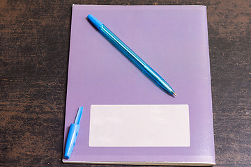 Image showing On the old table is a notebook and a pen with an open cap