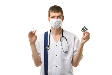 Image showing Male doctor holding a syringe with medicine in one hand and pills in the other hand, isolated on white background